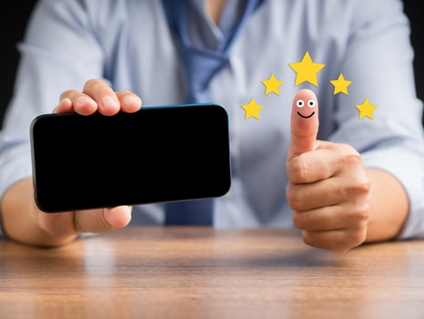 Hand with thumb up for smiley face icon and holding a smartphone photo