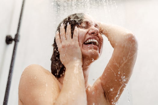 Brunette woman crying in the shower under cold water jet photo