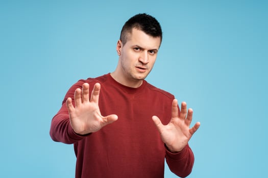 Serious man showing stop sign with both hands on blue background photo