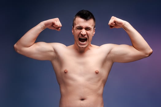 Man showing muscles and screaming with effort on blue background photo