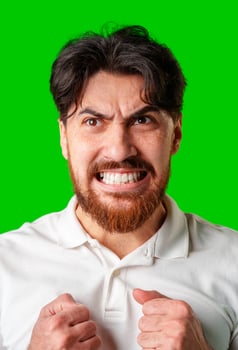 A man expresses intense frustration with a furious gesture against a bright green backdrop photo