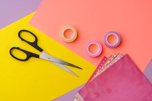Scissors and decorative tape on colorful craft paper in a bright workspace photo