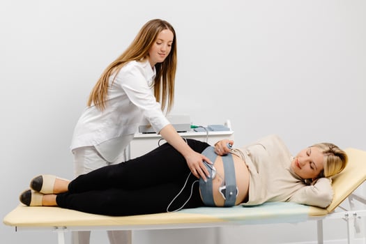 Doctor prepares a pregnant woman for checking fetal heartbeat by fetal monitoring. photo