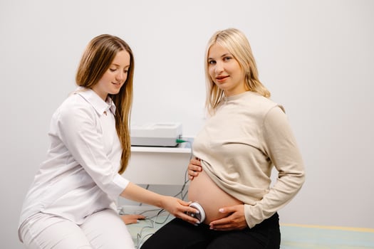 Doctor prepares a pregnant woman for checking fetal heartbeat by fetal monitoring. photo