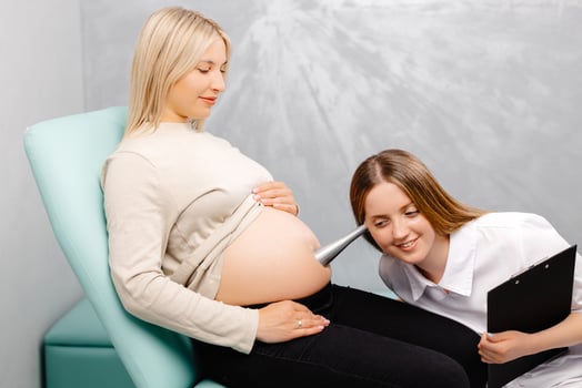 A gynecologist leans a stethoscope to a pregnant woman's belly and listens to the baby's heartbeat photo