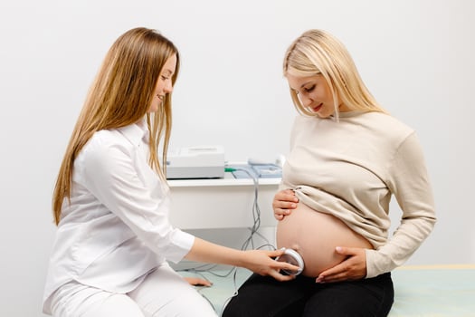 Doctor prepares a pregnant woman for checking fetal heartbeat by fetal monitoring. photo