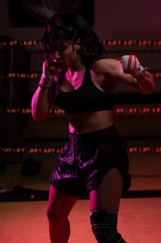 female Latina boxer with her hands bandaged working out at a training session at a gym throwing a punch photo