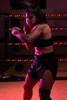 female Latina boxer with her hands bandaged working out at a training session at a gym throwing a punch photo