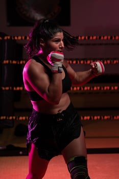female Latina boxer with her hands bandaged working out at a training session at a gym throwing a punch photo