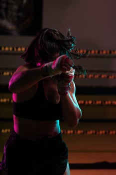 female Latina boxer with her hands bandaged working out at a training session at a gym throwing a punch photo