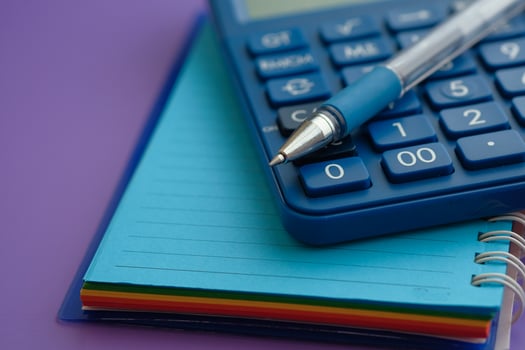 A calculator, notebooks, and a pen on a purple background, great for study and finance photo
