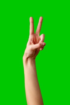 Hand Making Peace Sign Gesture Against Vibrant Green Background photo