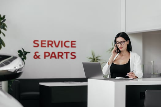 Sales woman use smartphone, have business call at car showroom. Car dealership client service and parts. Business Process and Problem Solving, Quality Control. Cell phone advise to choose, buy auto photo
