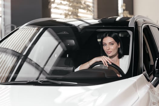 Portrait of gorgeous brunette woman make purchase in car showroom. Female sits inside of new, modern, electric car and look at sales agent. Concept for car rental or sale. Test drive. photo