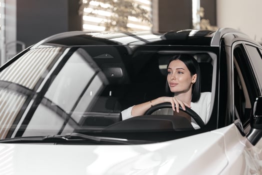Portrait of gorgeous brunette woman make purchase in car showroom. Female sits inside of new, modern, electric car and look at sales agent. Concept for car rental or sale. Test drive. photo