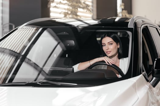 Portrait of gorgeous brunette woman make purchase in car showroom. Female sits inside of new, modern, electric car and look at sales agent. Concept for car rental or sale. Test drive. photo