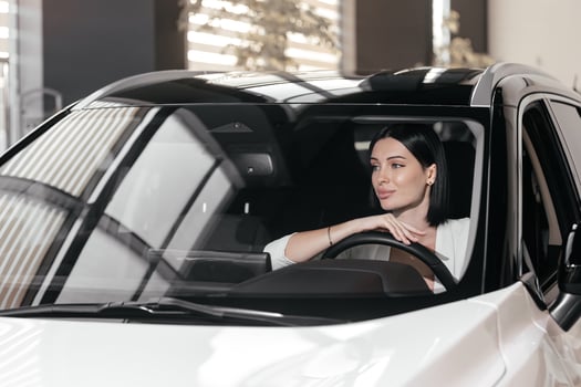 Portrait of gorgeous brunette woman make purchase in car showroom. Female sits inside of new, modern, electric car and look at sales agent. Concept for car rental or sale. Test drive. photo