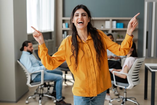 Excited businesswoman pointing up and laughing with colleagues in background photo