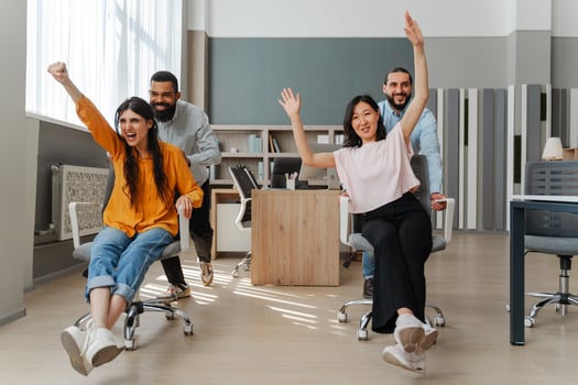 Happy multiethnic business team having fun racing on chairs in office photo