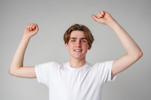 Young Man Celebrating Success With Arms Raised in a Joyful Gesture Indoors photo
