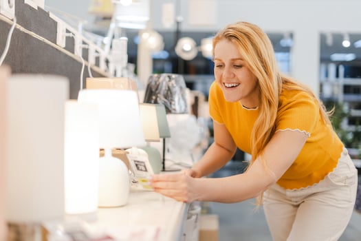 Smiling young woman holding lamp while choosing in decor department in the shopping center photo