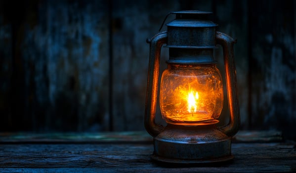 A lantern with a candle inside is lit up in a dark room. The warm glow of the candle creates a cozy and inviting atmosphere. The lantern is placed on a wooden surface photo