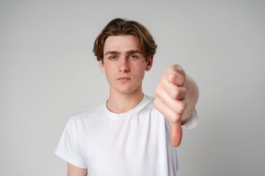 Young Man Giving a Thumbs Down Gesture Against a White Background photo