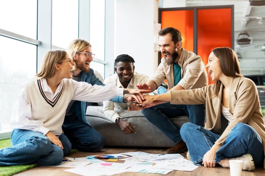 Excited multiethnic team celebrating success putting hands together photo