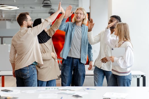 Diverse multinational team giving high five celebrating success in modern office photo
