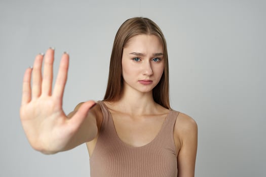 Young Woman in Fashionable Outfit Standing Against a Neutral Backdrop Showing Stop Gesture photo