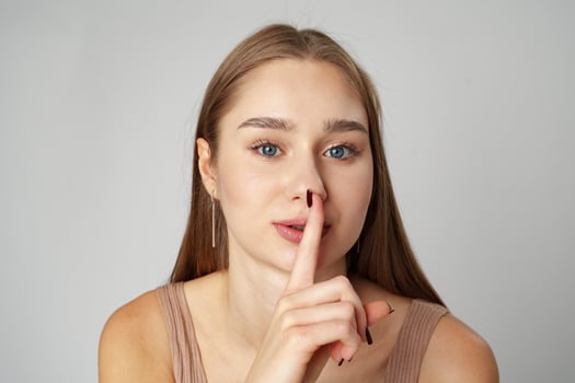 Young Woman Making a Hush Gesture against gray background photo