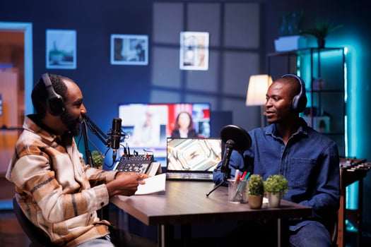 Black man with notebook is interviewing social media star and using audio equipment to record the program. Online radio host casually talking with influencer in home studio, recording podcast episode. photo