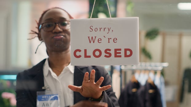 African american smiling storekeeper closing clothing store at night after selling entire inventory. BIPOC retail worker turning opened message sign on fashion boutique door in mall department photo