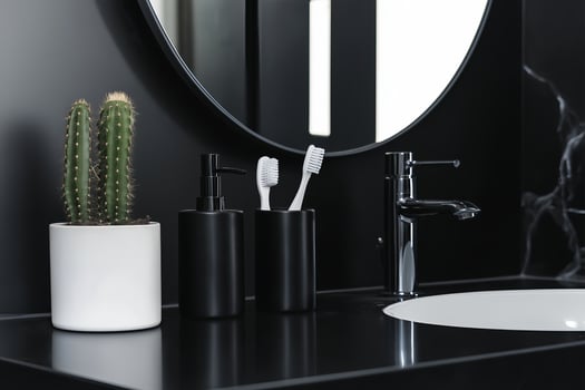 a minimalist bathroom counter showcases sleek black soap dispensers alongside a white toothbrush holder arranged on a matte black counter top photo