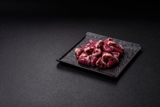 Raw chicken hearts with salt, spices and herbs photo