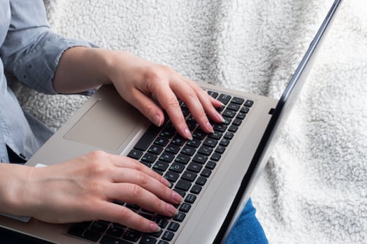 Woman sitting on a sofa working at computer hands. Close up. photo