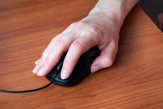 Hand holding computer mouse. Close up. Wooden table. photo