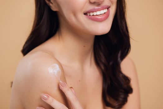 Beauty portrait of laughing beautiful half naked woman smiling and applying face cream photo