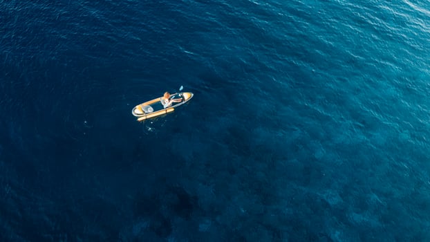 Woman floating on kayak in blue ocean. Drone view photo