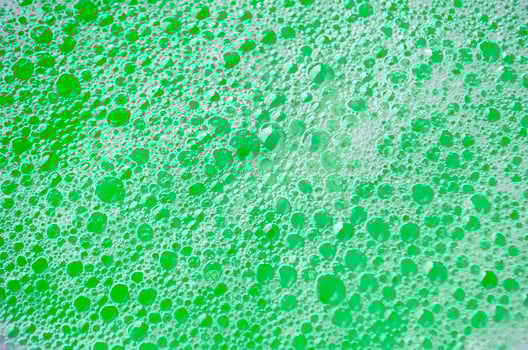 Top view bubbles rising slowly through a thick, green colored liquid photo