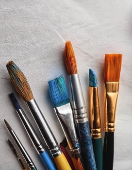 Paint and brushes lie on a white canvas. Creative Activities photo