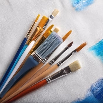 Paint and brushes lie on a white canvas. Creative Activities photo