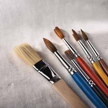 Paint and brushes lie on a white canvas. Creative Activities photo