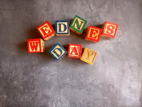A photo of a wooden block with the words wednesday written on it, styled in isolation with space for text.