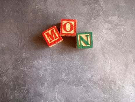 A photo of a wooden block with the words monday written on it, styled in isolation with space for text.