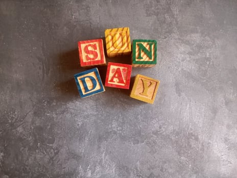 A photo of a wooden block with the words sunday written on it, styled in isolation with space for text.