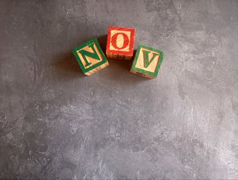 A photo of a wooden block with the words november written on it, styled in isolation with space for text.