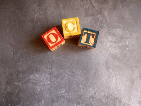 A photo of a wooden block with the words october written on it, styled in isolation with space for text.