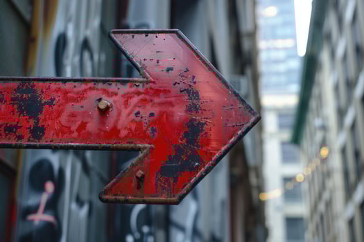 Rusty red arrow sign pointing right in urban alleyway photo