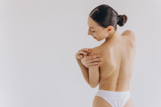 Cropped back rear view young nice lady woman with slim body perfect skin wearing nude top bra lingerie stand hold hands on thighs isolated on white background. Lifestyle diet fit concept photo